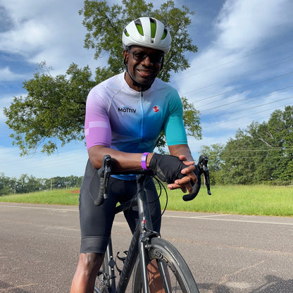 Man standing astride a bicycle, wearing a colorful cycling jersey